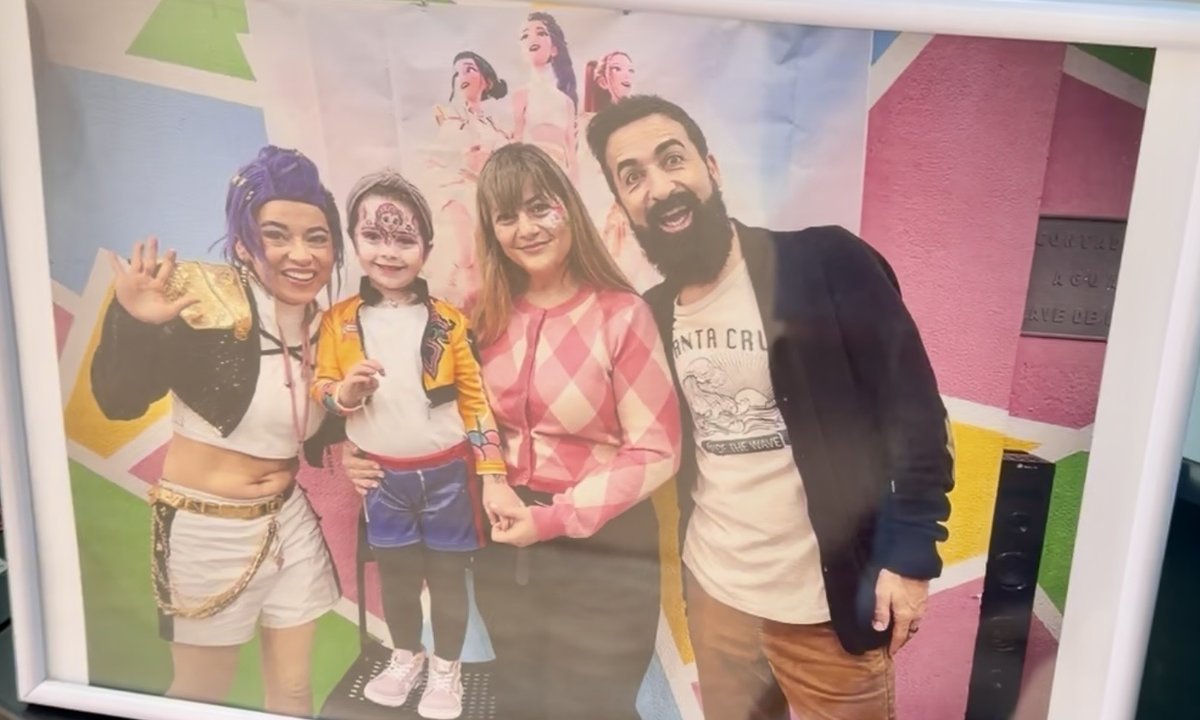 Foto de recuerdo enmarcada en una fiesta Bichitos: peque caracterizada con la animadora temática y su familia, lista para llevar a casa.